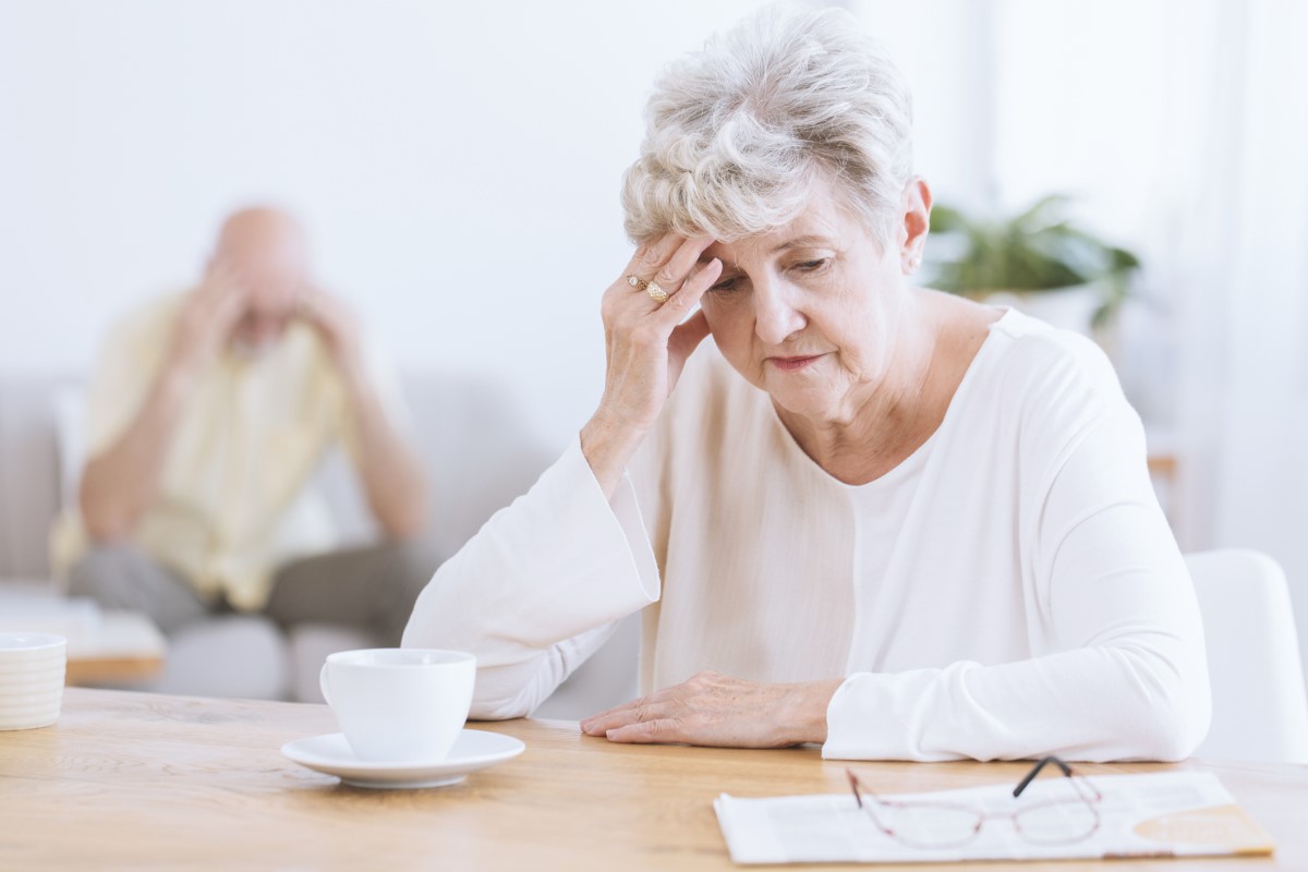 Beynin nörolojik fonksiyonlarının bozulması, olası Alzheimer hastalığı nedeniyle başını tutan yaşlı kadın. Ön planda, başı öne eğik, eline yaslanmış yaşlı kadın