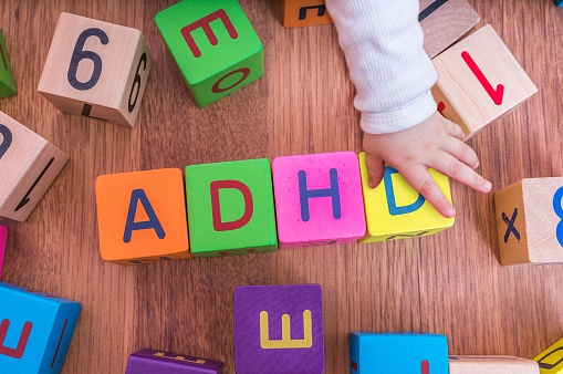 ADHD ismini oluşturacak şekilde düzenlenmiş çocuk harf küpleri, çocuğun eliyle