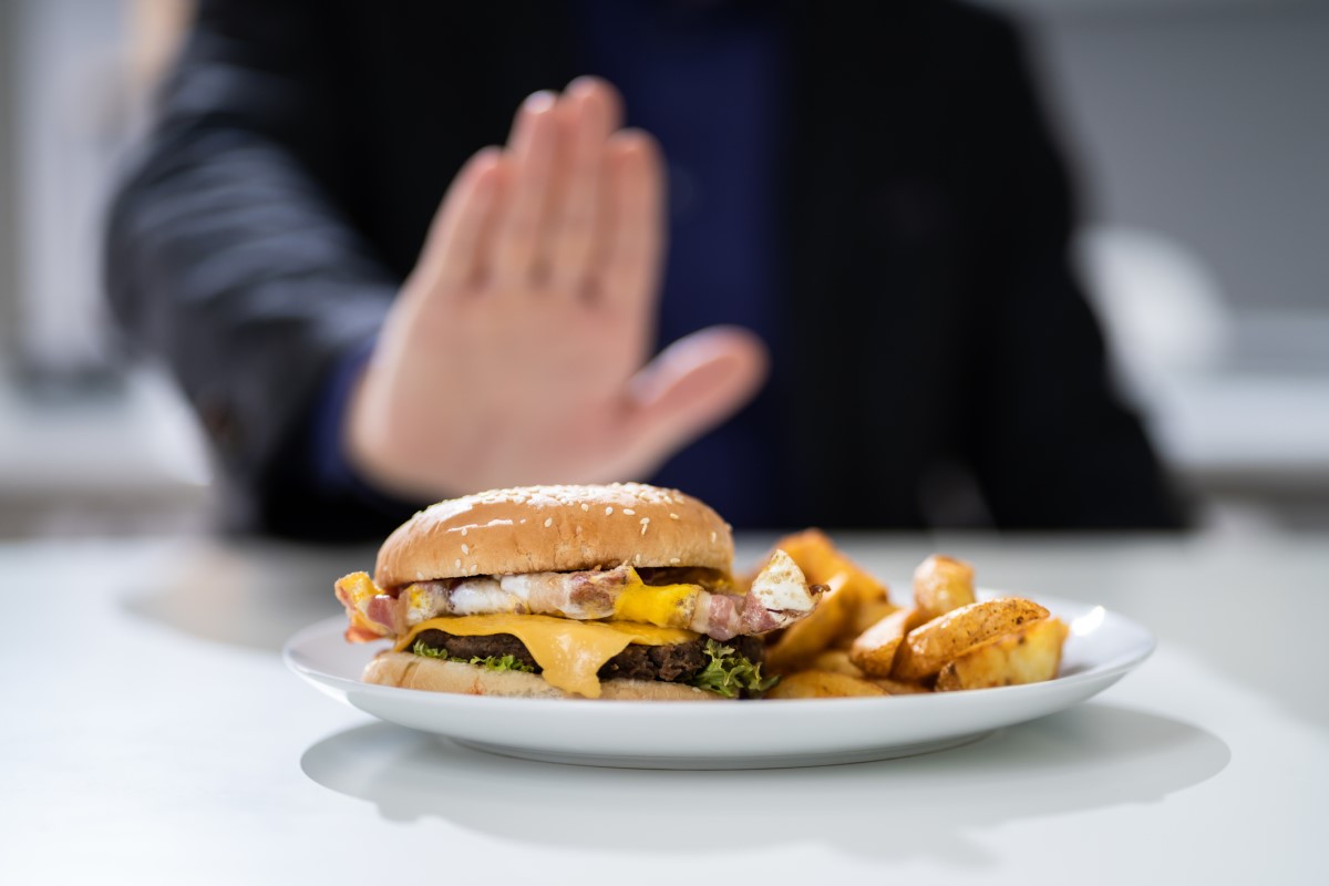 Mide ekşimesi nedeni olarak uygunsuz yiyecek - bir erkeğin reddettiği tabakta bir hamburger